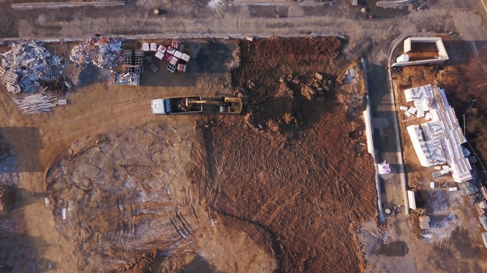 An overhead view of an excavator loading a truck on a construction site